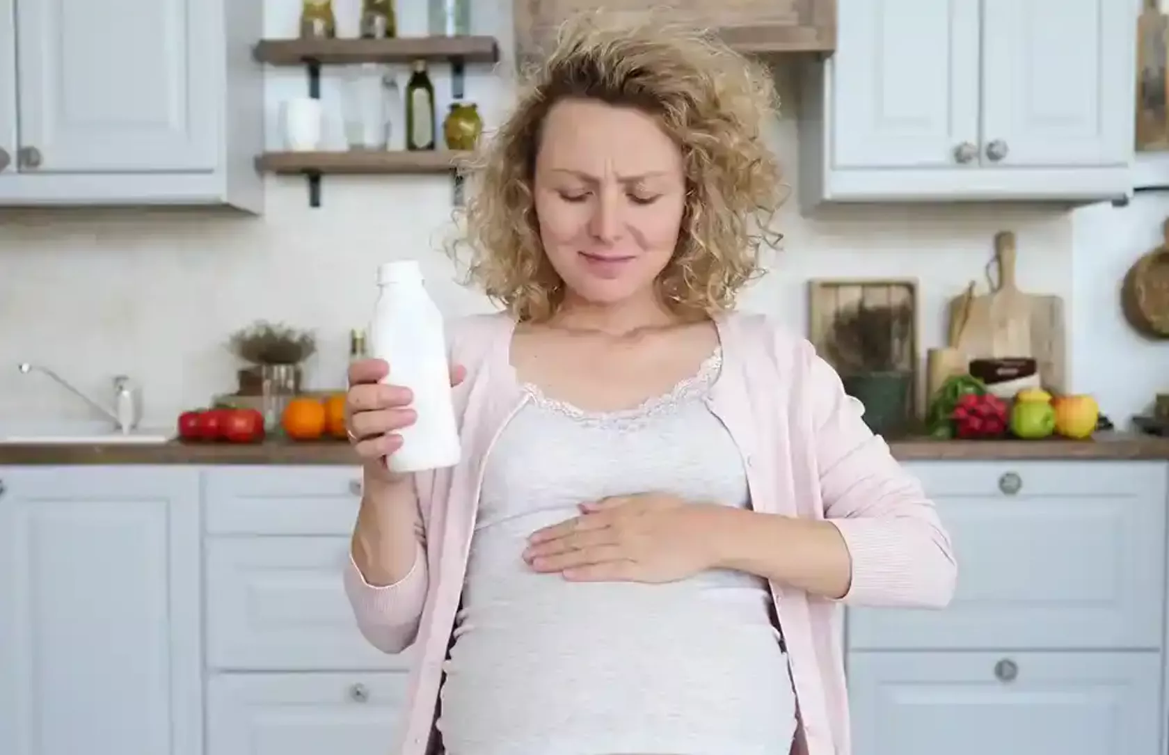 Hochschwangere Frau nimmt Medikament gegen Sodbrennen ein, hält die Hand auf den Oberbauch.