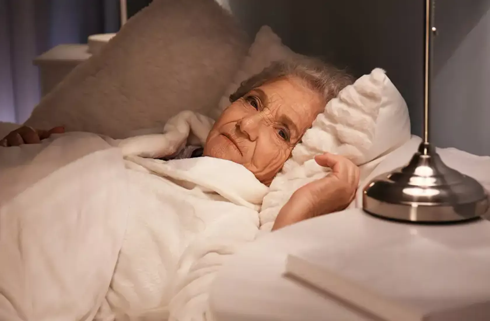 Seniorin liegt nachts schlaflos im Bett.
